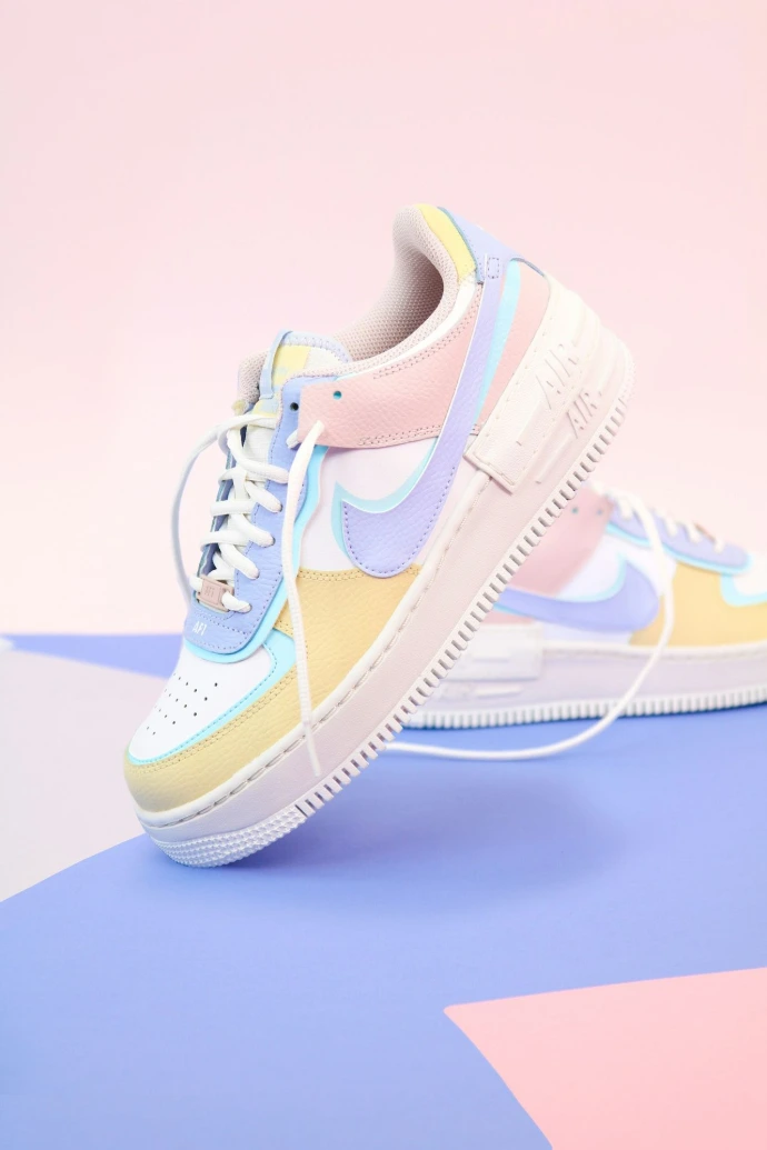 Pastel colored sneakers with white laces on a blue and pink geometric surface